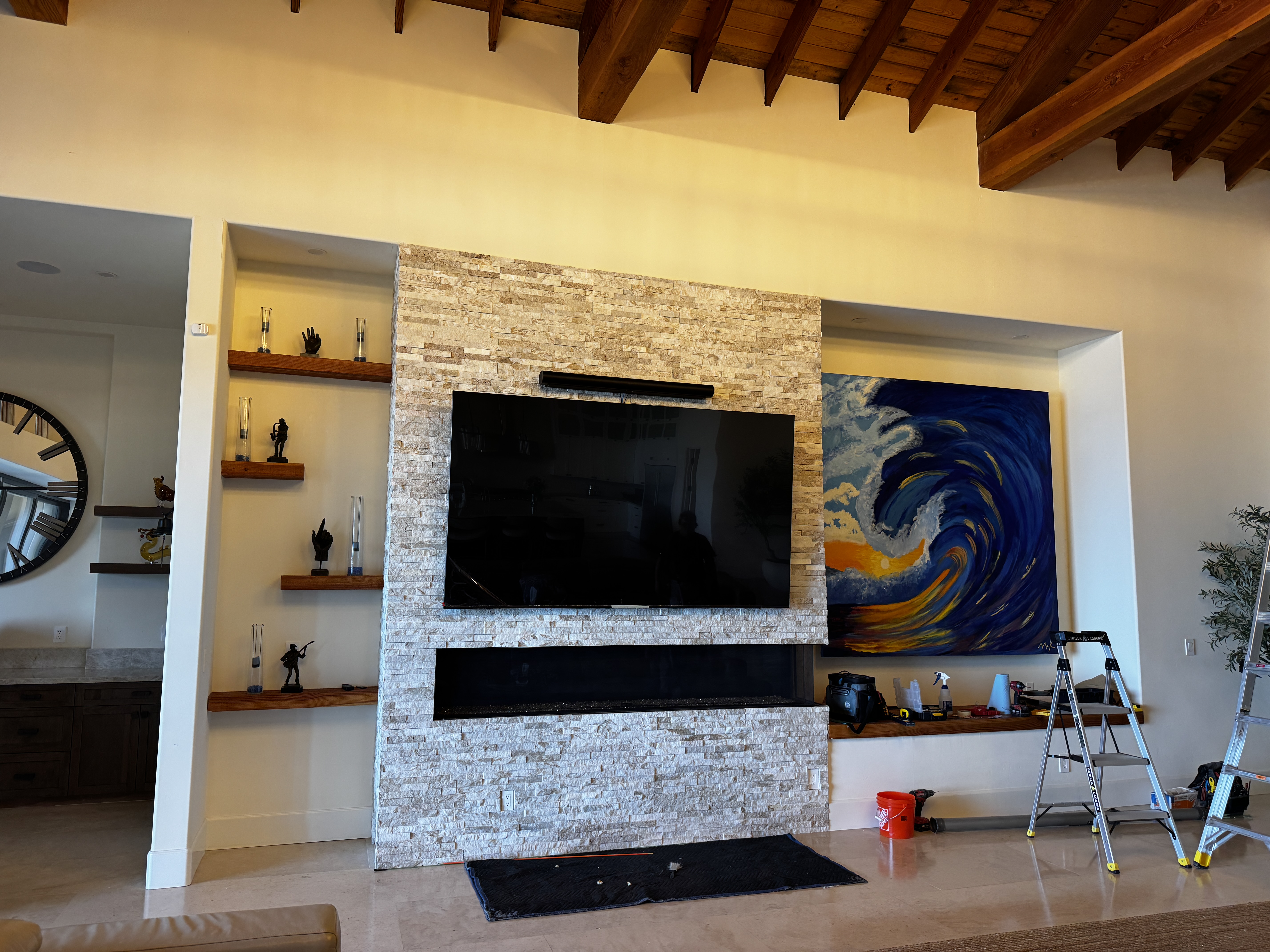 100-inch TV off — full room view showing scale against stacked stone fireplace wall